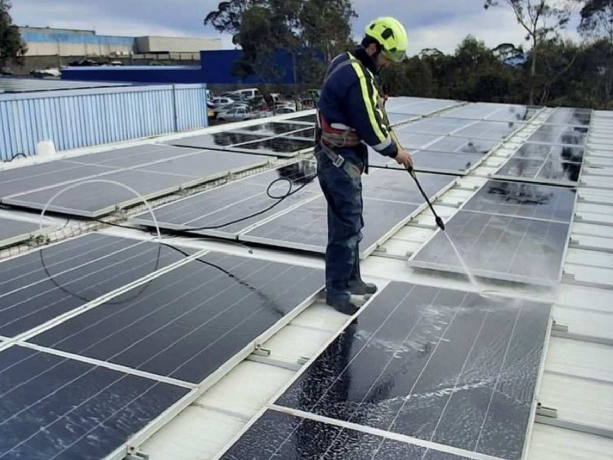 Técnico em equipamento de segurança a realizar manutenção de painéis solares no telhado